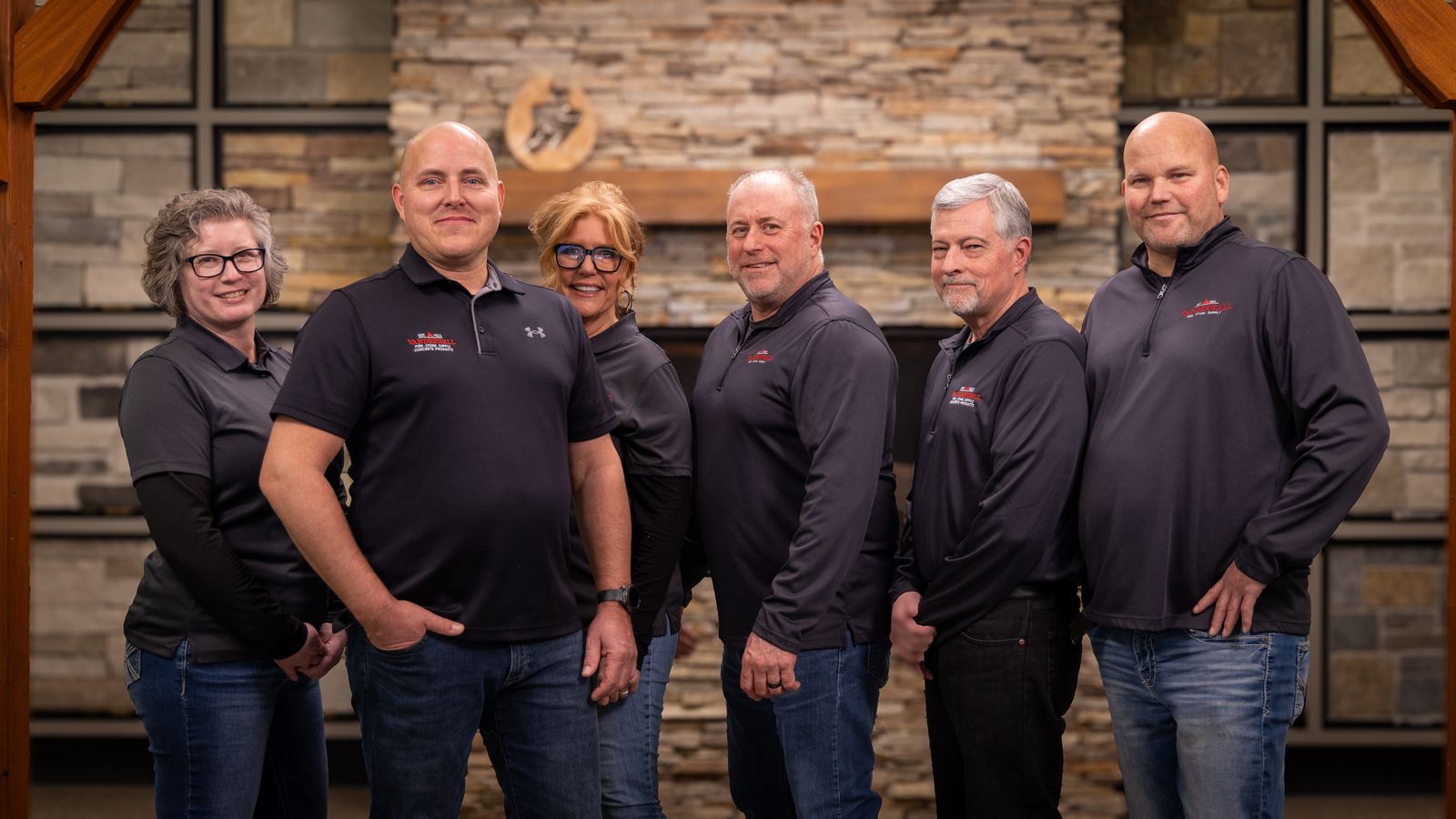 Six members of the VanderWall team in front of a stone fireplace