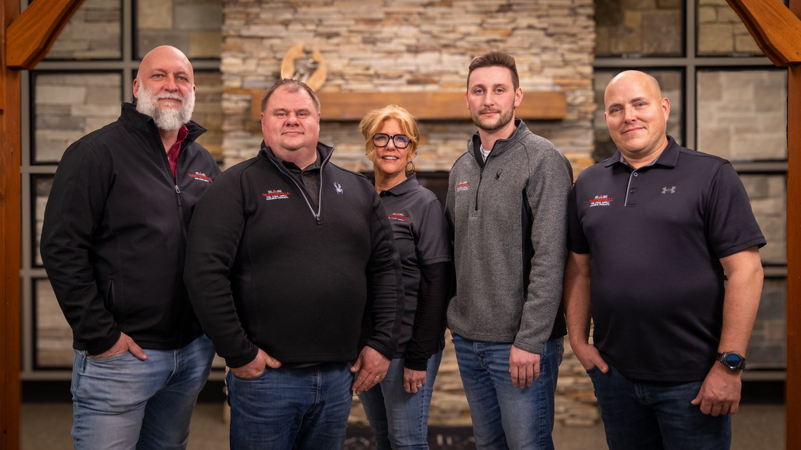 Five members of the VanderWall team in front of a stone fireplace