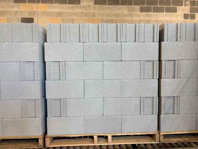 Full pallets of gray 8 inch concrete block stacked in alternating courses on wood pallets inside the VanderWall Brothers plant