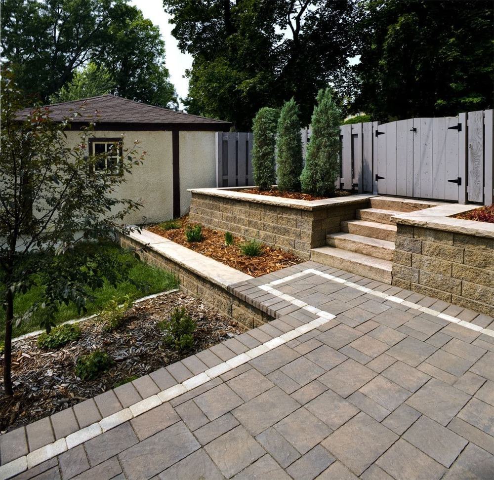 A paver walkway and steps beside a low stone wall
