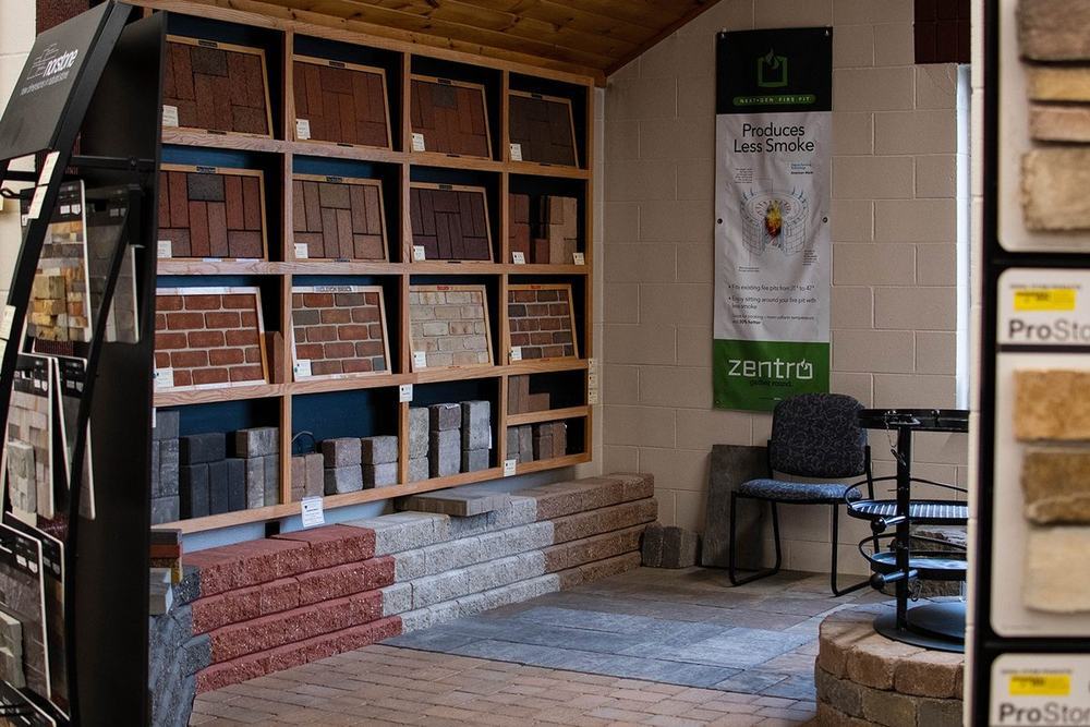 Brick and paver sample racks under the cedar roof of the outdoor showroom, with paver step displays alongside