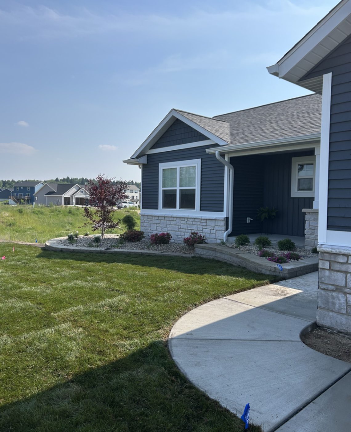 Stone veneer, a low edging wall and new plantings along the front of a house